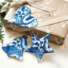 three blue and white ceramic stars are sitting next to a gift box with twine ribbons