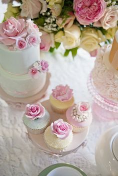 a table topped with three tiered cakes and cupcakes