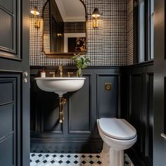 a bathroom with black and white checkered wallpaper, gold accents and a pedestal sink