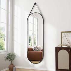 a mirror hanging on the wall in a living room next to a couch and window