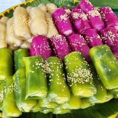 several different types of food are displayed on a plate with green leaves and sesame seeds