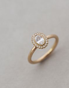 a gold ring with a white diamond in the center on a gray surface, close up