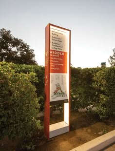 a large sign in the middle of a field with trees and bushes behind it that reads middlee