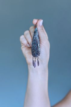 a woman holding up a piece of jewelry in her left hand and the other hand is holding it