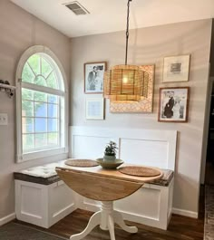 a table with a bowl on it sitting in front of a window and some pictures