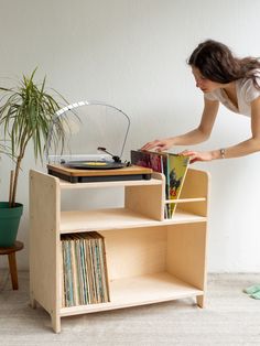 a woman bending over to pick up some records from a record player's shelf