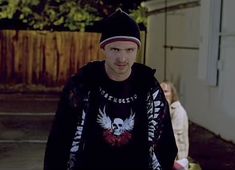 the young man is walking down the street wearing a skull shirt and beanie hat