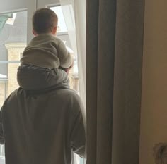 a man holding a child looking out the window