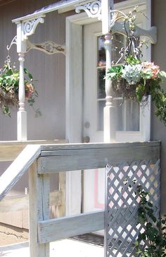 an old wooden bench with flowers hanging from it's sides on the front porch