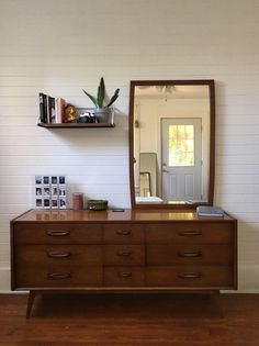 a wooden dresser sitting in front of a mirror on top of a hard wood floor