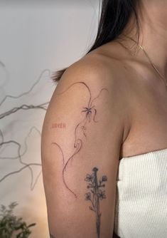 a woman with a tattoo on her arm holding a flower in front of her shoulder