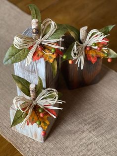 two small wooden pumpkins decorated with leaves and twine bows on top of a table