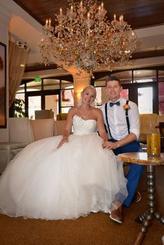 a bride and groom pose for a photo in front of a large chandelier