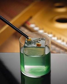 a close up of a drink on a table with a piano in the back ground