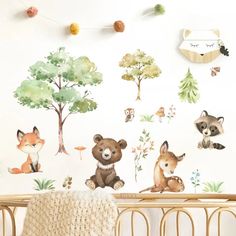 a baby's crib with wall decals and woodland animals on the wall