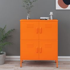 an orange cabinet is in the corner of a room with a potted plant next to it