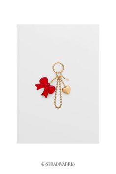 a red bow and heart shaped keychain on a white background