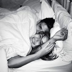 a man and woman laying in bed under the covers with their arms around each other