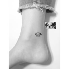 a small black and white dog on the side of a person's foot with tattoos