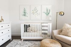 a baby's room with white furniture and paintings on the wall, including a crib