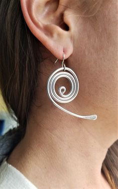 The earrings are made of Aluminum with the wire technique.Modern earrings.  Aluminum Silver Earrings.  Modern Designe.Silver Spiral Large Earrings. Handmade. This spiral shape earrings are a statement piece, the perfect accessory to complete a stunning outfit look. Ideal for a casual fashion style. Materials:  - Aluminum wire (2.0 mm). The material I use to wrap aluminum wire, that means, is not heavy at all. Aluminum is lightweight and will never tarnish. I give it a slightly hammered texture a Silver Wire Earrings, Aluminum Jewelry, Spiral Shape, Stunning Outfits, Outfit Look, Large Earrings, Modern Earrings, Wire Earrings, Jewelry Silver