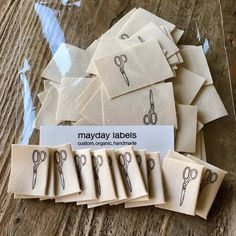 several pairs of scissors sitting on top of a wooden table next to some tags that say mayday labels