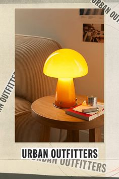 a yellow lamp sitting on top of a wooden table next to a book and cup