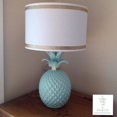 a blue glass lamp sitting on top of a wooden table next to a white shade