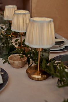 the table is set with plates, silverware and lamps