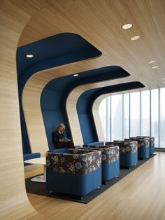 a woman sitting on a couch in a room with wooden floors and blue curved walls