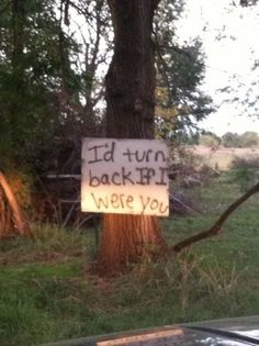 a sign that reads i'd turn back by we're you next to a tree