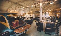 an old car is parked in the middle of a large room with tables and chairs