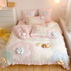 a bed with pink and blue flowers on the comforter, pillows and pillow cases