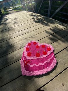 a crocheted heart shaped cake sitting on top of a wooden deck