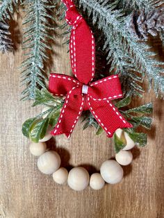 a red and white christmas ornament on a wooden table with pine cones, evergreen branches and balls