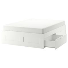 a white bed with drawers underneath it on a white background and the bottom drawer is open