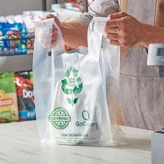 a person holding a plastic bag in front of a store counter with food items on it