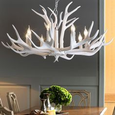 a chandelier made out of antler branches hangs over a dining room table