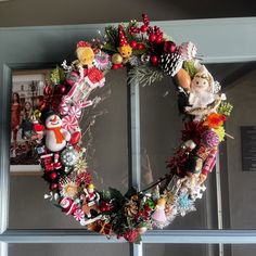 a christmas wreath is hanging on the front door with ornaments and decorations around it,