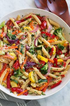 a bowl filled with pasta and veggies on top of a marble countertop