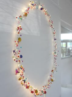 a circular light fixture hanging from the side of a wall covered in glass beads and lights