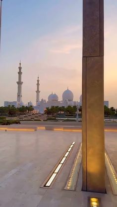 the sun is setting over an empty square in front of two tall buildings with lights on them