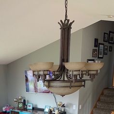 a chandelier hanging from the ceiling in a room with stairs and pictures on the wall