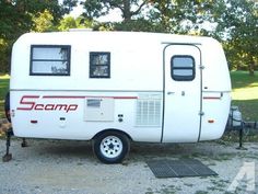 the camper is parked on gravel near trees