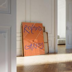 an orange sign with blue writing on it sitting in the middle of a room next to a doorway