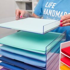 a person standing next to a stack of colored folders on top of each other