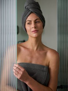 a woman with a towel wrapped around her head looking at the camera while standing in front of a mirror