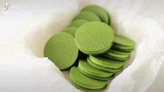 a bunch of green cookies sitting in a white paper bag on top of a table