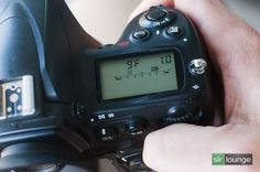 a person holding a camera with a digital clock displayed on the screen and in front of it