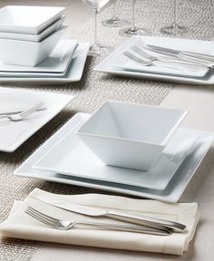 the table is set with white dishes and silverware